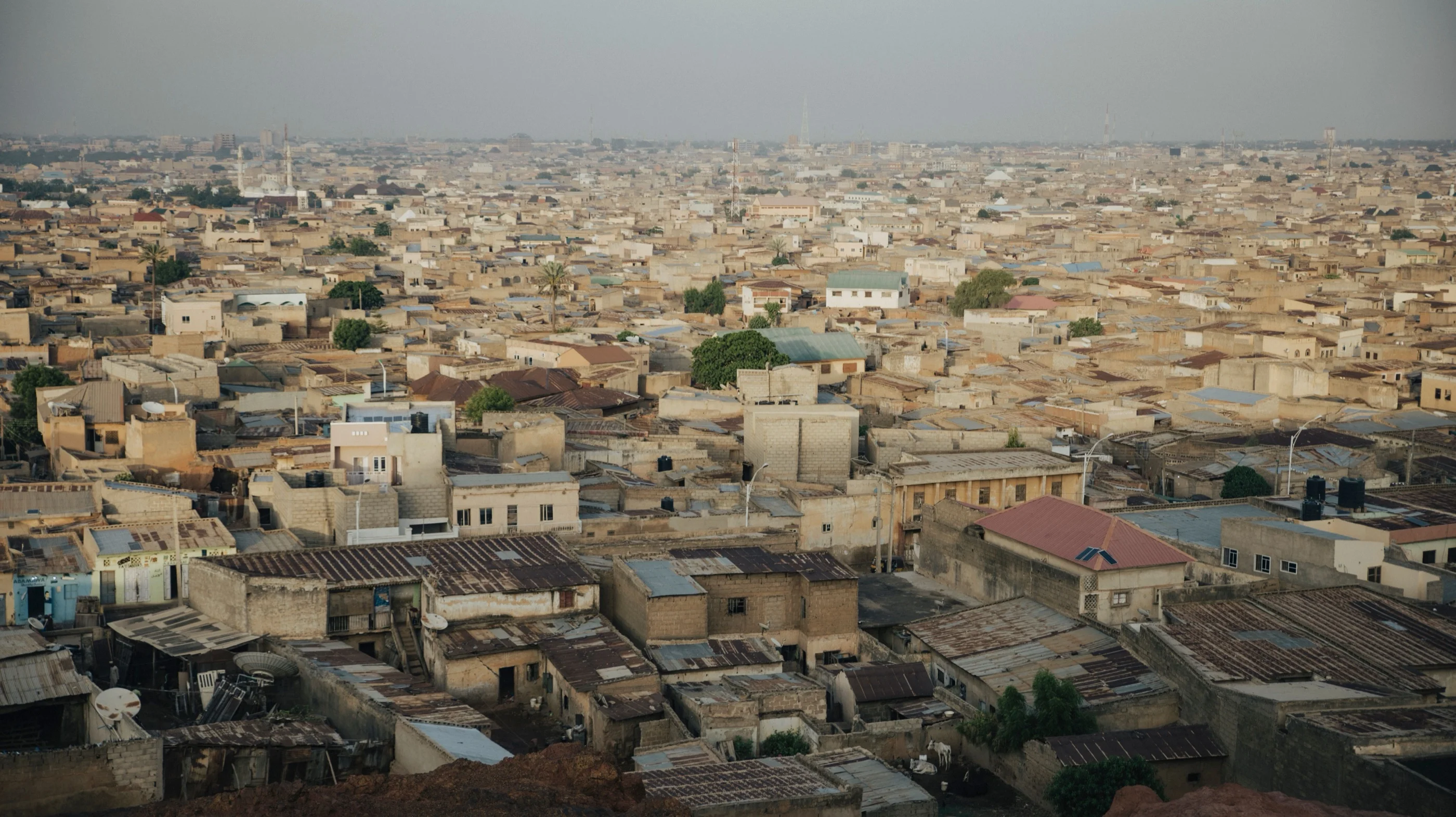 Elevated view over Kano, a dense sand-coloured city of flat roofs stretching to a hazy horizon