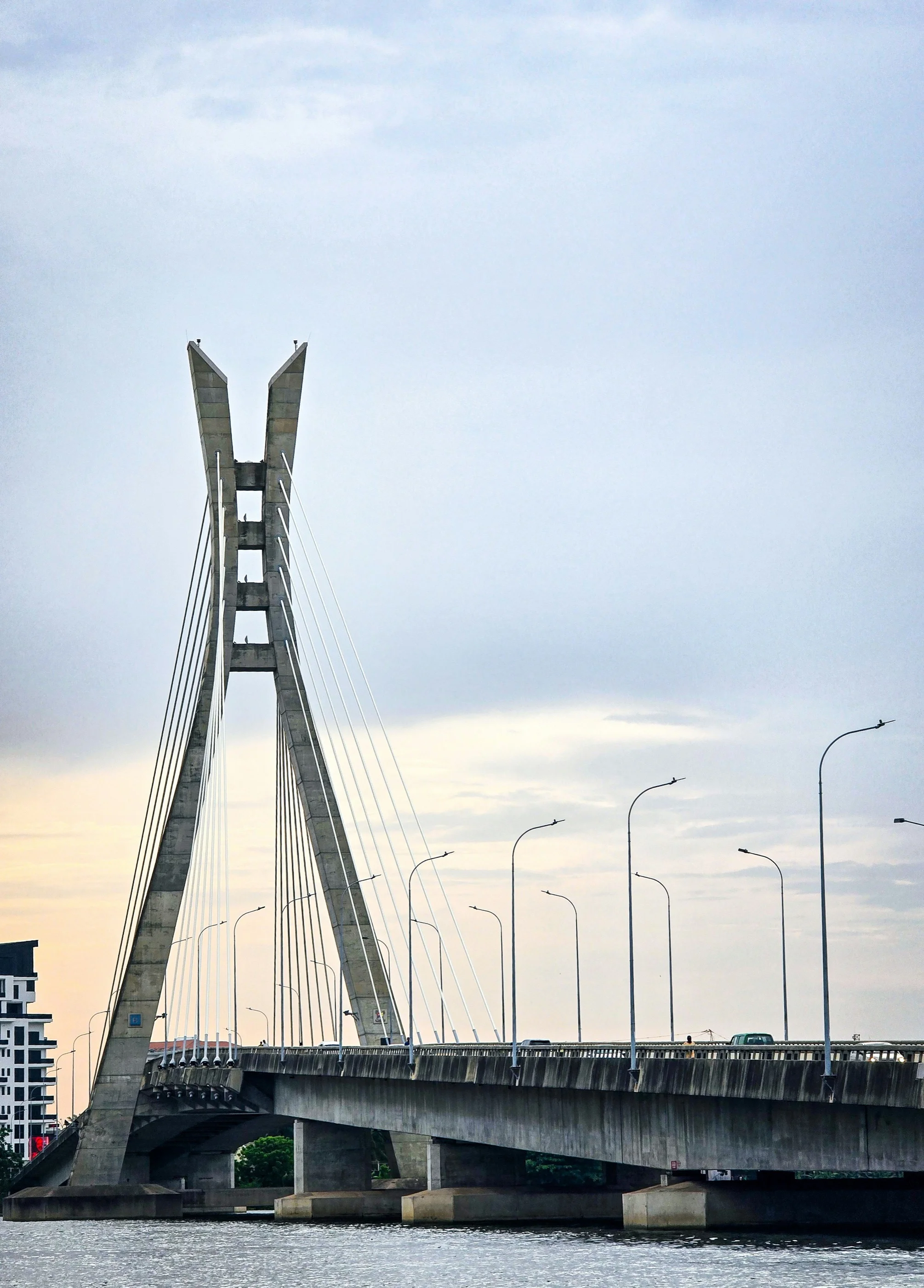 The Lekki–Ikoyi Link Bridge in Lagos, its X-shaped pylon over calm water under a pale evening sky